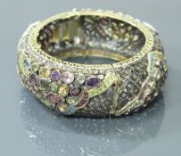 An 18 carat gold and silver mounted multi gem set bangle including diamond, ruby, sapphires,