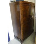 A mid 20th Century walnut bow fronted two door wardrobe with basic fitted interior