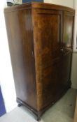 A mid 20th Century walnut bow fronted two door wardrobe with basic fitted interior
