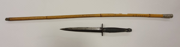 An SAS dagger with ribbed handle and engraved blade, housed in a leather scabbard,