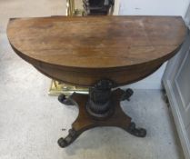 A Victorian rosewood fold over card table of demi-lune form raised on a lotus leaf carved centre