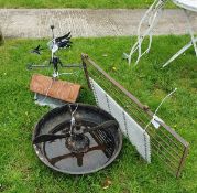 A wrought iron feeder, together with a weather vane, housed on a terracotta tile, a gate section,