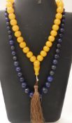 A graduated lapis lazuli beaded necklace together with an amber beaded necklace with tassel