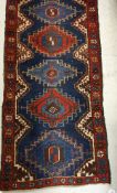 A Persian runner, the central panel set with repeating diamond shaped medallions on a blue ground,
