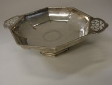 A George VI silver dish of octagonal form with pierced side handles raised on a pedestal base
