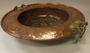 A Middle Eastern copper and brass dish with embossed foliate decoration and hinged brass handles