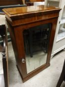 A Victorian walnut music cabinet with single mirrored door enclosing four shelves together with an