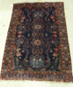 A Persian carpet, the central panel set with all-over floral design on a dark blue ground,