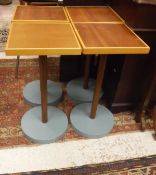 A set of four occasional tables with cross-banded wooden tops above a simple pedestal to circular