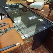 A modern glass top desk or table on two L shaped pedestal supports