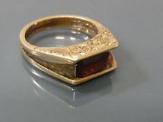 A 9 carat gold emerald cut garnet set ring, the shoulders with foliate decoration, total weight 4.