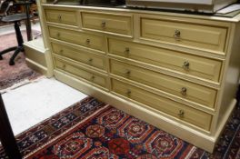 A large cream multi chest of drawers together with a matching dressing mirror retailed by