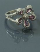 A 9 carat white gold diamond and pink sapphire set cluster ring in the form of a flower head,