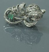 A platinum diamond and emerald set brooch in the form of a floral spray and bow, total weight 7.