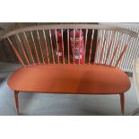An Ercol beech framed and orange painted stick back love seat on turned splayed supports united by