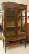 An Edwardian mahogany inlaid and glazed display cabinet above two short drawers on square tapering