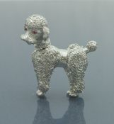 A mid 20th Century 14 carat white gold brooch in the form of a poodle with ruby set eyes and