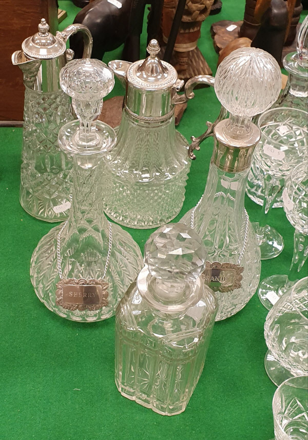 Two claret jugs with white metal mounts and three various decanters two with bottle tags "Sherry"