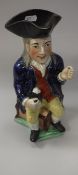 A 19th Century pottery character jug as a seated long haired gentleman with jug of ale (pipe