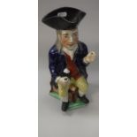 A 19th Century pottery character jug as a seated long haired gentleman with jug of ale (pipe