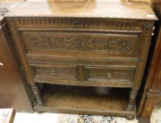 A late Victorian Gothic Revival oak side cabinet with rising top over two drawers on turned and