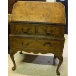 A 1930's burr walnut bureau with sloping fall enclosing an unfitted interior over two short and one