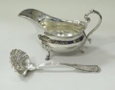 A silver baluster shaped sauce boat with acanthus thumb piece to the scroll handle raised on three
