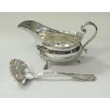 A silver baluster shaped sauce boat with acanthus thumb piece to the scroll handle raised on three