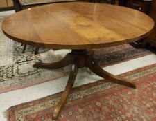 A modern oak dining table on a central pedestal to quadruped base,