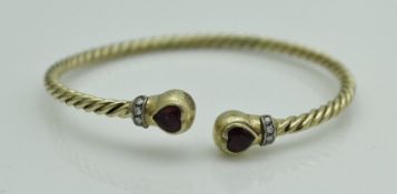 An 18 carat gold torque style bangle set with love heart shaped rubies and diamonds to the ends,