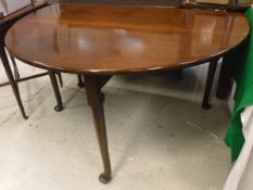 An early 19th Century mahogany drop-leaf dining table raised on turned legs to pad feet