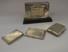 A collection of three silver cigarette boxes / cases and a silver faced desk calendar on ebonised
