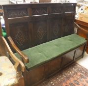 An 18th Century oak settle, the panelled back with carved lozenge medallions,