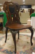 A set of four 19th Century walnut panel seated hall chairs with shield-shaped backs raised on