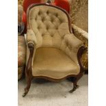 A Victorian show frame salon chair with buttoned back and serpentine front raised on brass caps and