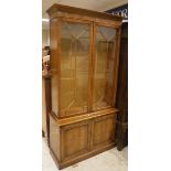 A 20th Century yew wood veneered display cabinet with two glazed doors over two panelled cupboard