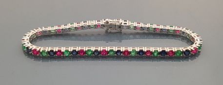 A 14 carat white gold tennis bracelet set with rubies, sapphire and emeralds, 10.