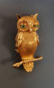 A 14 carat gold brooch in the form of an owl on a branch with emerald set eyes, 5.