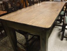 A pine kitchen table with metal edging to the top on a green painted base