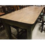 A pine kitchen table with metal edging to the top on a green painted base