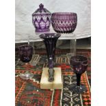 A collection of amethyst and amethyst overlaid cut glass ware including two cornucopia vases,