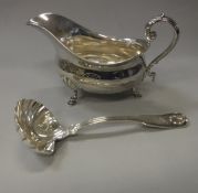 A silver baluster shaped sauce boat with acanthus thumb piece to the scroll handle raised on three