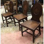 A set of three late Georgian mahogany oval medallion back panel seat hall chairs on square