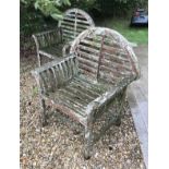 A pair of teak garden seats of slatted construction with domed backs in the manner of Lutyens