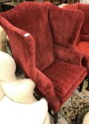 A 19th Century red upholstered wing back chair with shell carved cabriole front legs to ball and