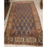 A Persian carpet, the central panel set with repeating hook motifs on a dark blue ground,