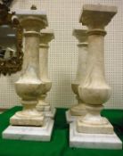 A set of four grey viened white marble column lamps of urn form raised on square sockel bases