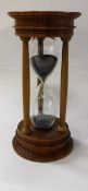 A modern walnut mounted blown glass "Urbino" hourglass sand timer bearing silver medallion to top