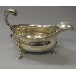 A George II silver sauce boat with scroll handle raised on three hoof feet (by David Hennell,