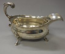 A George II silver sauce boat with scroll handle raised on three hoof feet (by David Hennell,